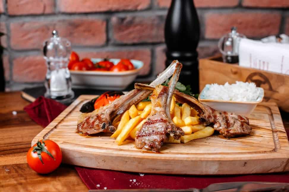 rack of lamb with tomatoes and spices on a wooden board