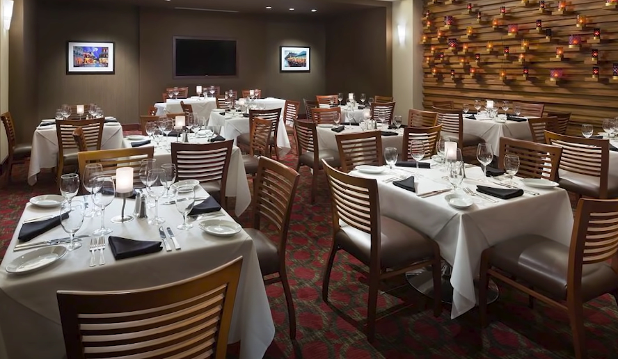 Interior view of Ruth's Chris Steak House with tables, chairs, and neatly arranged utensils.