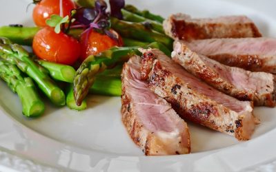 Sliced steak with asparagus and tomatoes on a plate.